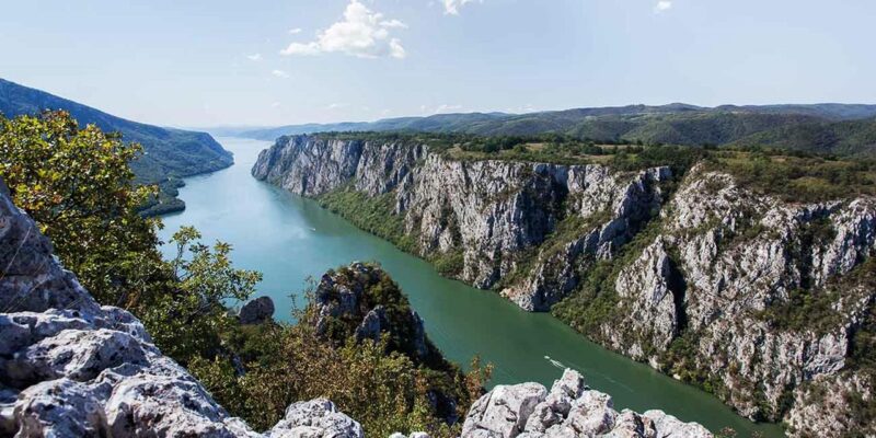 Pogled na Đerdapsku klisuru sa strmim liticama koje okružuju reku Dunav, pružajući impresivan prirodni pejzaž